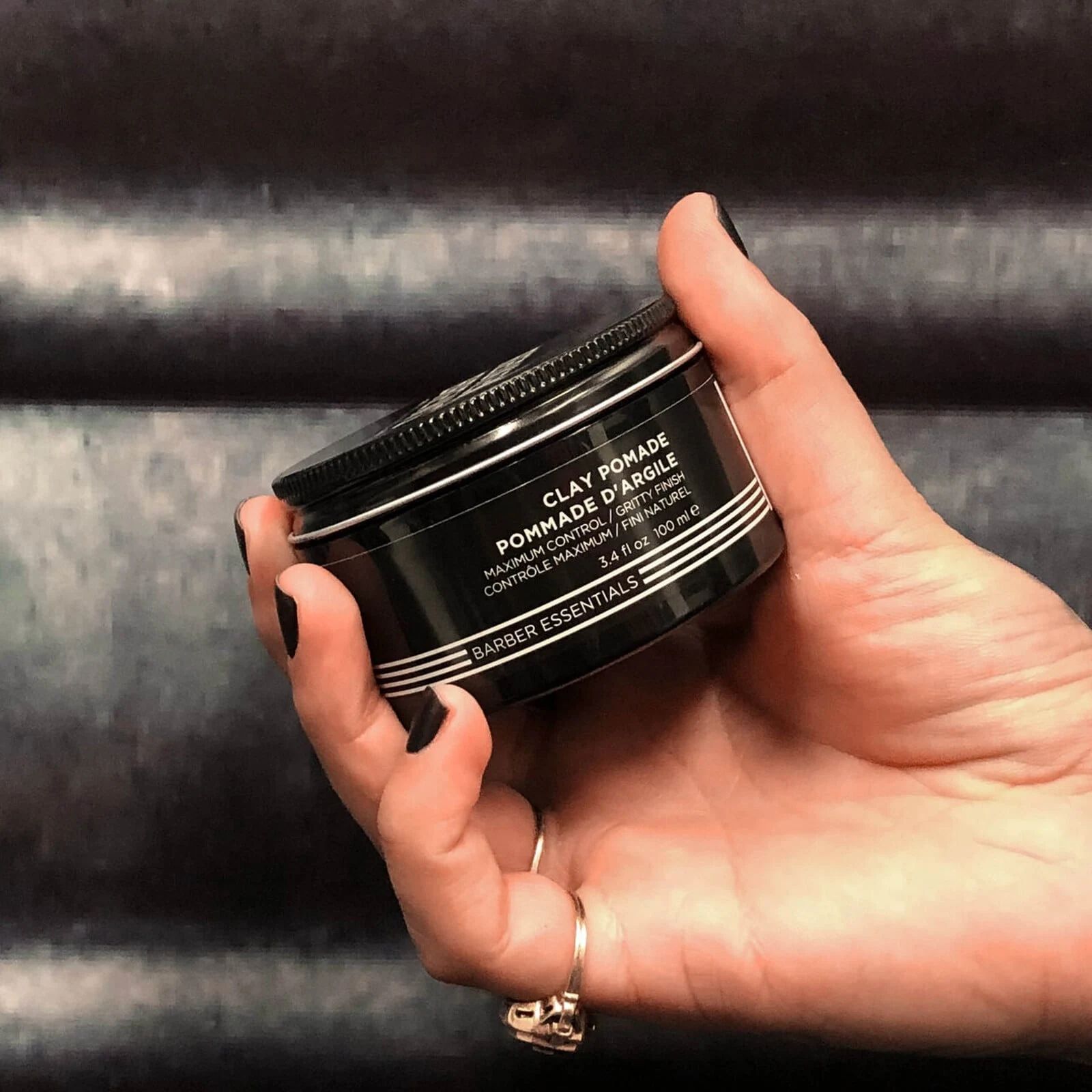 Redken Brews Clay Pomade in a stylist hand for scale