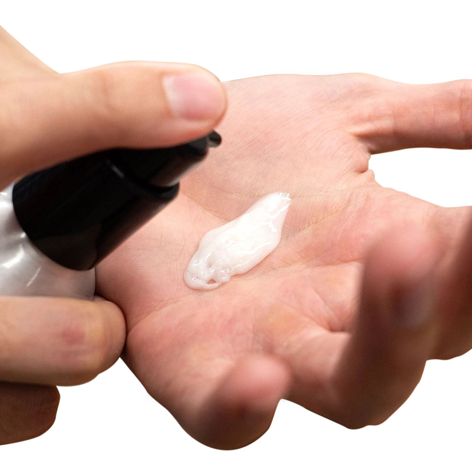Uppercut Deluxe Control Cream: Hand applying a small amount of cream from a bottle onto another hand against a white background, view 2