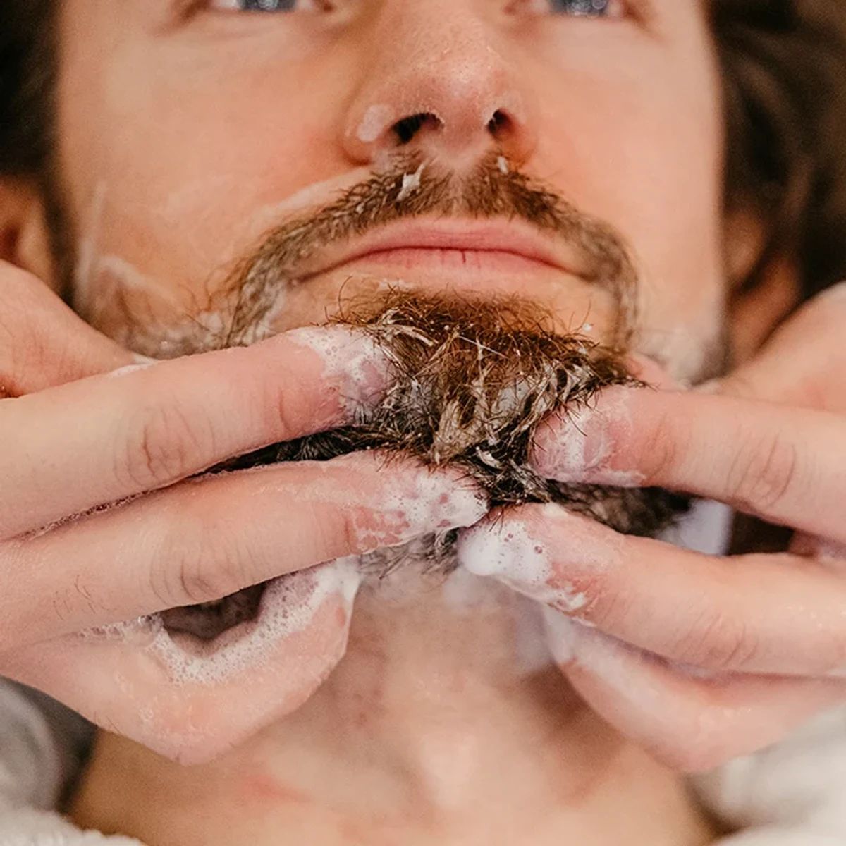 Man working Proraso beard wash lather into a wet beard